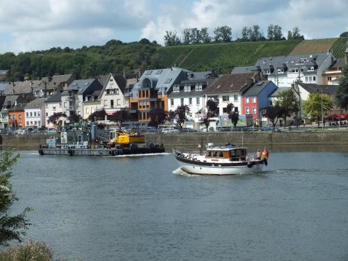 a boat traveling down a river in a town at Rezas Restaurant Gästehaus in Oberbillig