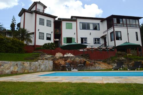 una casa grande con piscina frente a ella en Pousada Villa Verde en Lavras Novas