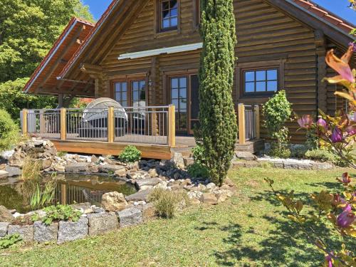 una cabaña de madera con un estanque frente a ella en Wooden holiday home with sauna, en Teunz