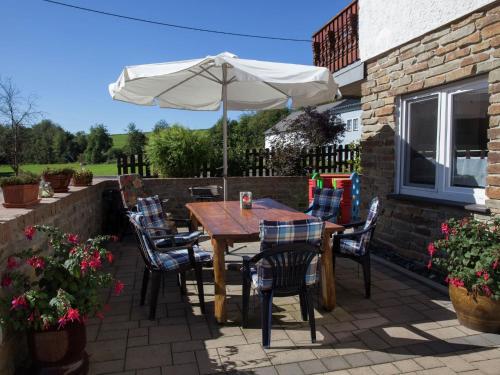 a table and chairs with an umbrella on a patio at Quiet apartment along a stream in Halenfeld in Sellerich