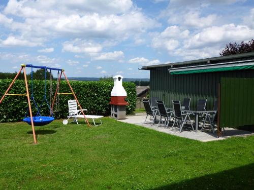a playground with chairs and a swing in a yard at Apartment in Leudersdorf Eifel with terrace in Üxheim