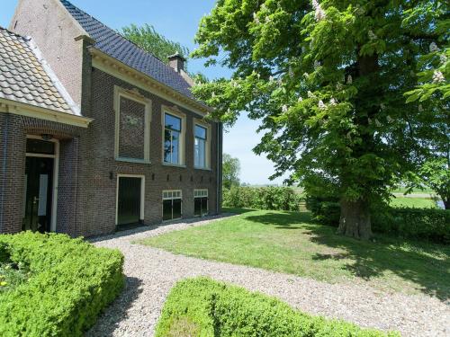 una vieja casa de ladrillo con un árbol en el patio en Charming house in Easterlittens on a Frisian farm, en Wommels