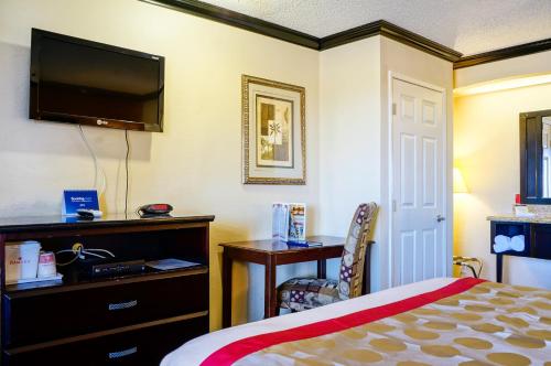 a hotel room with a bed and a desk and a television at Ramada by Wyndham Ontario Airport & Convention Center in Ontario