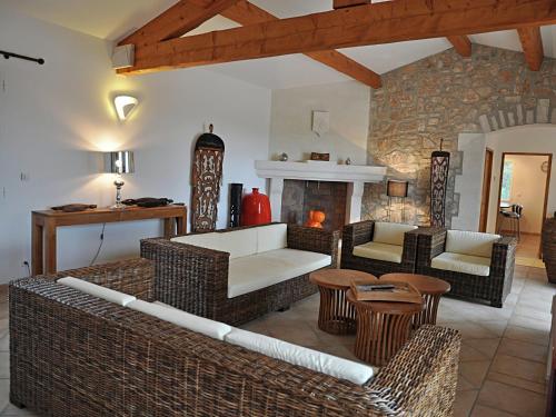 a living room with wicker furniture and a fireplace at Holiday home with views and private pool in Saint-Victor-de-Malcap