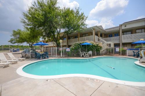 a swimming pool in front of a building with chairs and umbrellas at Motel 6-Baytown, TX - Baytown East in Baytown