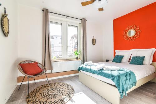 a bedroom with a bed with an orange wall at Gare - Redline - Centre Ville in Colmar