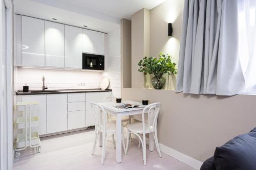 a kitchen with white cabinets and a table and chairs at Fly Rooms Madrid Airport in Madrid
