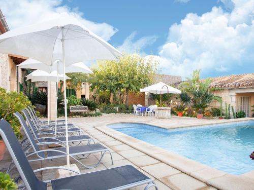 a pool with chairs and umbrellas next to a house at Belvilla by OYO Villa Campanet Vell in Campanet