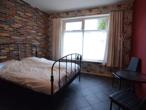 een slaapkamer met een bed en een bakstenen muur bij Holiday home near the Frisian Eleven Cities in Mantgum