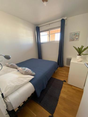 - une chambre avec un lit doté de rideaux bleus et d'une fenêtre dans l'établissement T2 face à la mer, à Sète