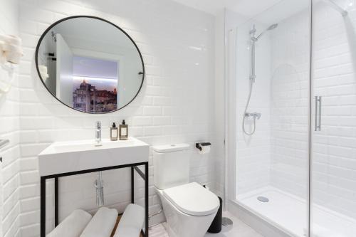a white bathroom with a toilet and a mirror at Fly Rooms Madrid Airport in Madrid