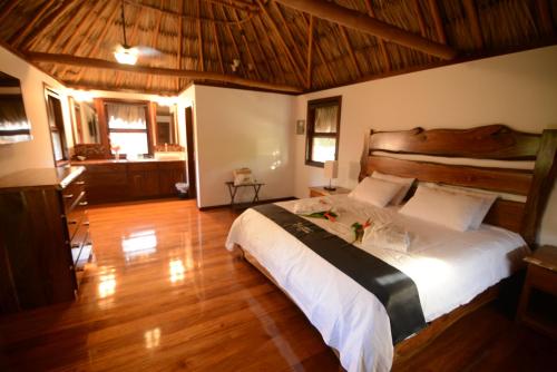a bedroom with a large bed and a wooden floor at El Ben Cabañas in Caye Caulker