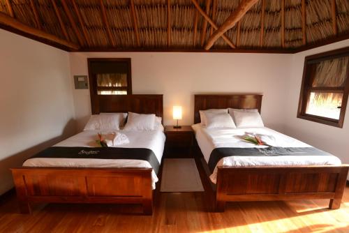 a bedroom with two beds and a lamp in it at El Ben Cabañas in Caye Caulker
