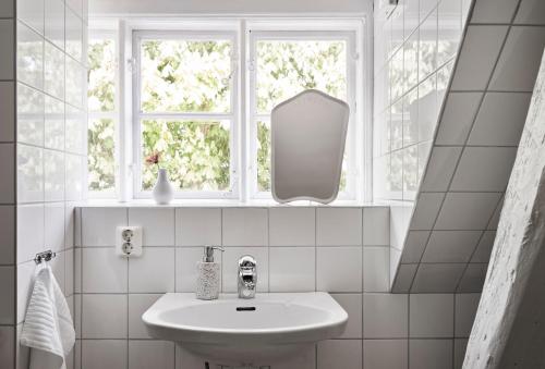 a white bathroom with a sink and a window at Hammenhögs gästgivaregård in Hammenhög