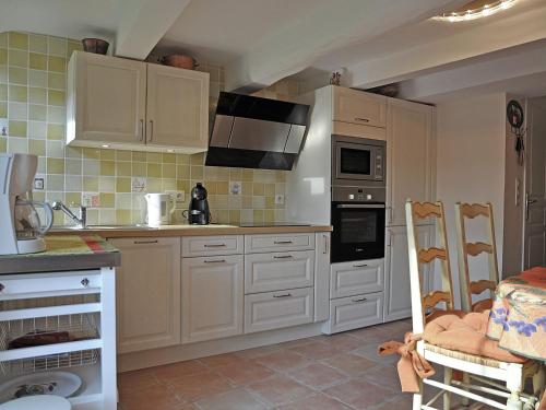 uma cozinha com armários brancos e um forno com placa de fogão em Sunny house in Fayence with terrace em Fayence