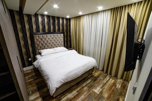 a bedroom with a large bed with white sheets at Apartmani Milanovic in Bijeljina