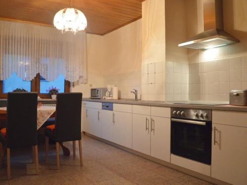 a kitchen with white cabinets and a table with chairs at Holiday home in Haserich with terrace in Haserich