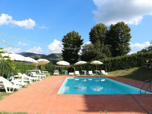 een zwembad met witte stoelen en parasols bij Belvilla by OYO Villa Gaio in Vicchio