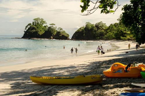 a beach with two kayaks and people on the beach at Hotel Arenas en Punta Leona in Jacó