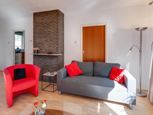 sala de estar con sofá y silla roja en Cozy vacation home with a private garden, en Mantinge