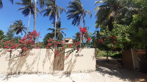 a fence with red flowers on it with palm trees at Villa Jodie Fortim in Fortim