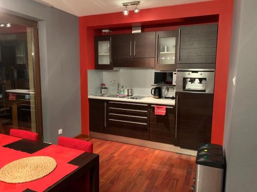 a kitchen with brown cabinets and a red wall at Apartament Hong Kong in Jurata