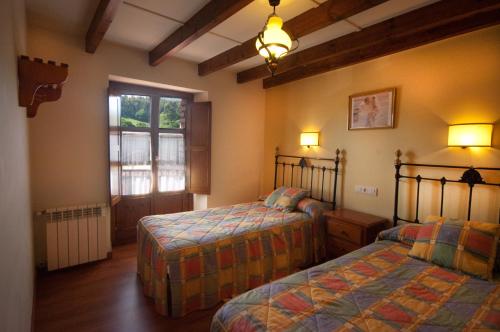una camera da letto con due letti e una finestra di Apartamentos el Cueto de los Collado a Villanueva de Pría