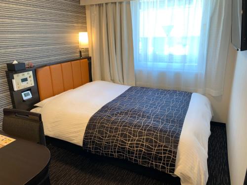 una stanza d'albergo con un letto e una finestra di APA Hotel Joetsu Myoko-Ekimae a Jōetsu