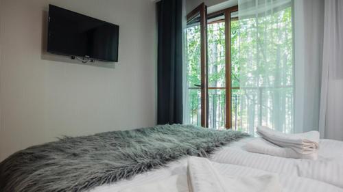 1 dormitorio con 1 cama y TV en la pared en Trevilles Apartamenty - Green Hills, en Szklarska Poręba