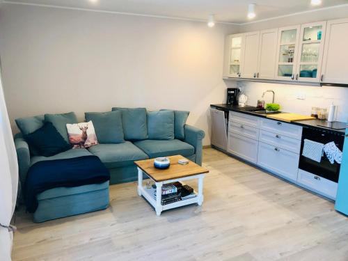 uma sala de estar com um sofá azul e uma cozinha em Apartament by Karol em Międzywodzie