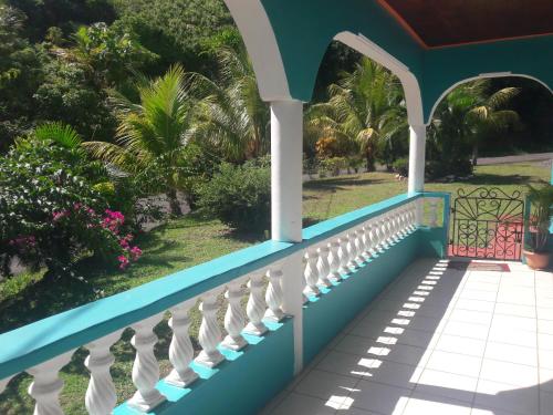 een huis met een blauw en wit balkon met palmbomen bij Danglez Bed & Breakfast in Bataka