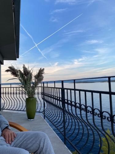 a person sitting on a balcony looking out at the ocean at THE VIEW **** in Račišće