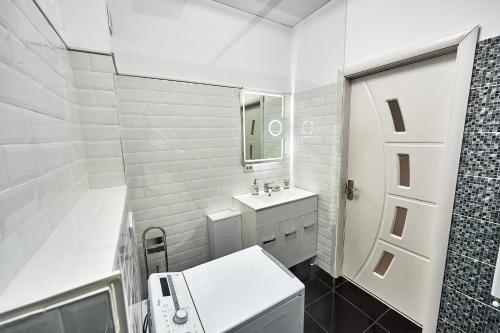 a white bathroom with a sink and a mirror at Ana Apartament in Năvodari