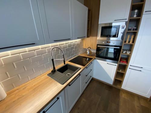 Una cocina con gabinetes blancos y un fregadero. en D&T by Tomazzo, en Třinec