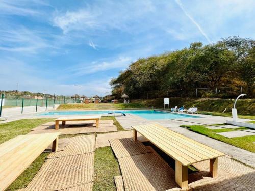 a pool with two wooden benches next to at El mirador de Los Sauces in Puerto Vallarta
