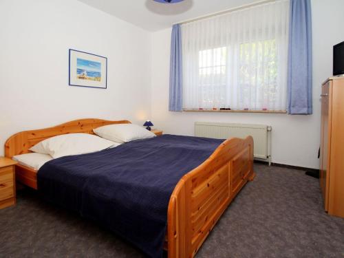een slaapkamer met een houten bed en een raam bij Apartment, Dornumersiel in Dornumersiel