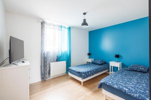 Cette chambre bleue comprend 2 lits et une télévision à écran plat. dans l'établissement logement 004 a 300m de la gare Mantes la jolie, à Mantes-la-Jolie