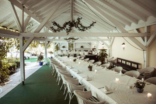 a long banquet hall with white tables and chairs at Hotel Limmerhof in Taufkirchen