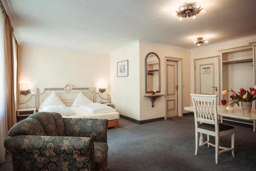 a hotel room with a bed and a chair at Hotel Limmerhof in Taufkirchen