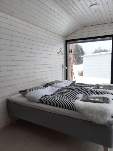 a bed sitting in a room with a window at Willa Rauha 1B in Lumijoki