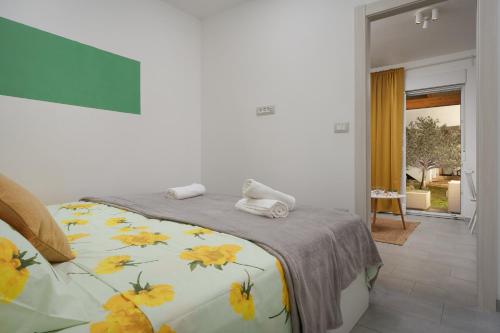 1 dormitorio con 1 cama con manta de flores amarilla en Apartments Elena Tia, en Medulin