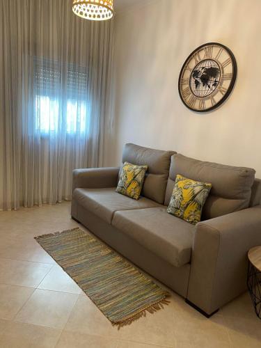 a living room with a couch and a clock on the wall at Casas da Praia in Nazaré