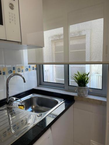 a kitchen with a sink and a window at Casas da Praia in Nazaré