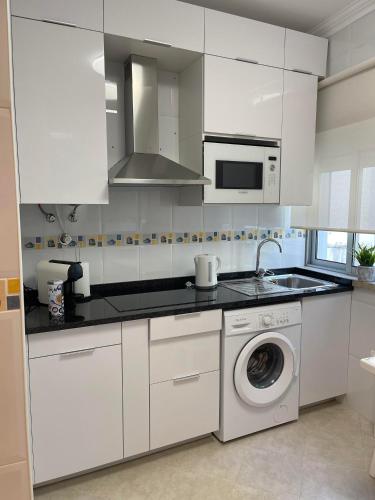 a kitchen with white cabinets and a washing machine at Casas da Praia in Nazaré