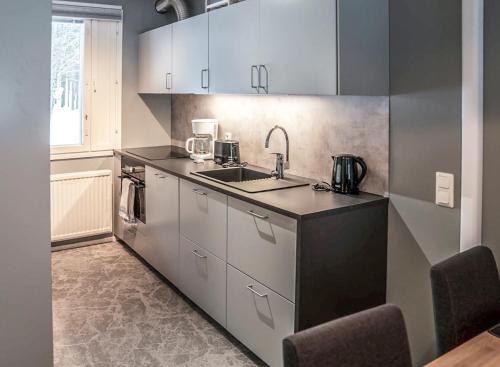 una cucina con mobili bianchi e un lavandino di Holiday Apartment Usva Kolmio a Suomutunturi
