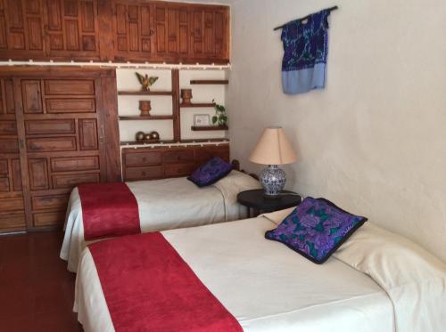 a room with two beds and a lamp on a table at Hotel Mi Casita in Taxco de Alarcón