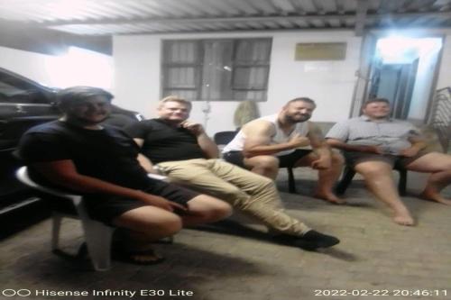 a group of men sitting on benches in a room at Maluti Backpackers in Phuthaditjhaba