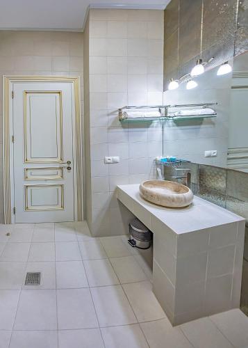 a white bathroom with a sink and a door at Vintage Hotel in Tbilisi City