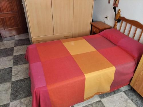 Una cama con una manta de colores encima. en Apartamento soleado y amplio, en Plasencia