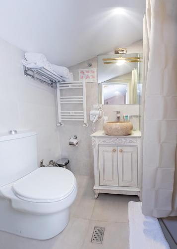 a white bathroom with a toilet and a sink at Vintage Hotel in Tbilisi City